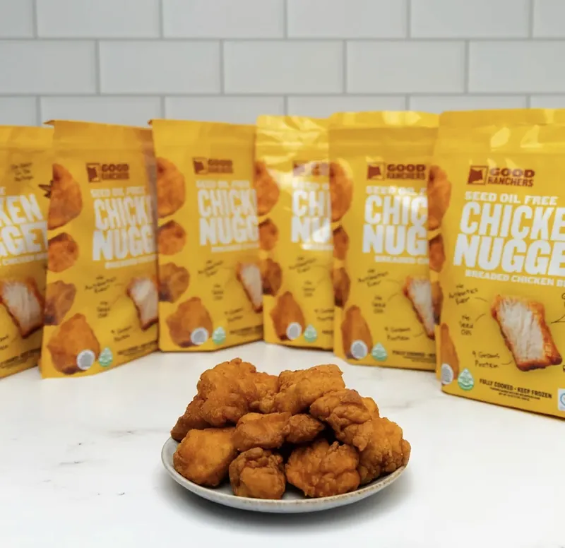 A plate of nuggets in front of a row of Good Ranchers Seed Oil Free Chicken Nuggets bags