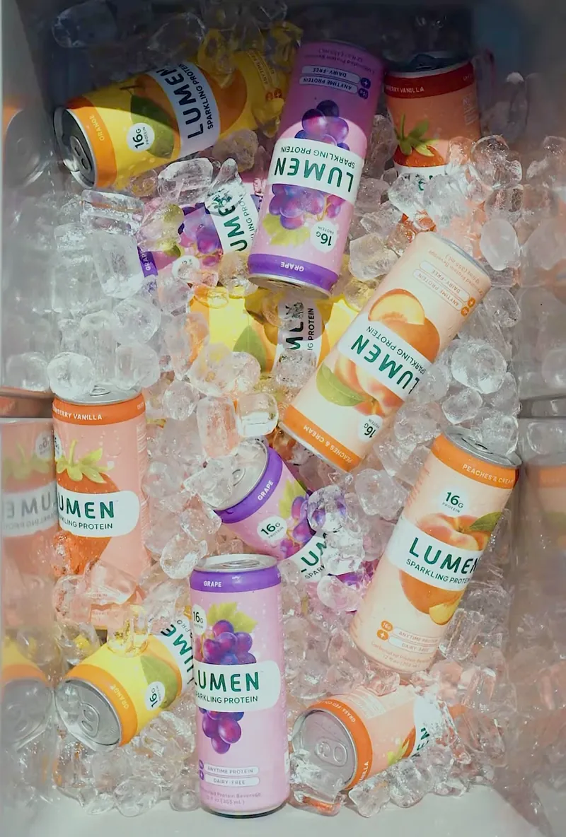 Lumen sparkling protein cans in grape, peach and orange packed in a cooler of ice