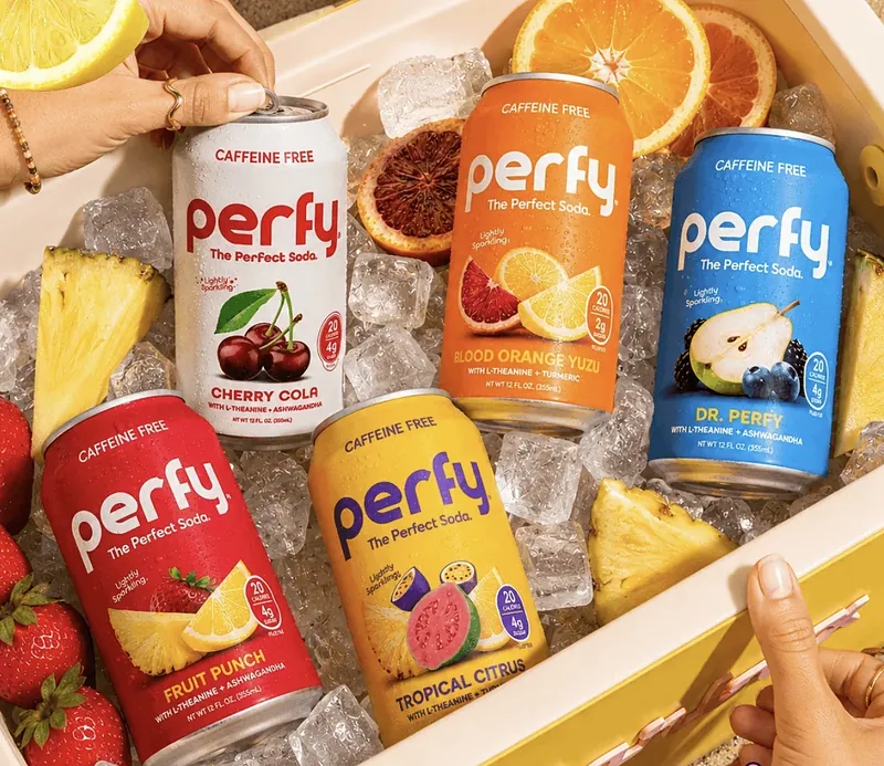 Perfy sodas in a cooler of ice with citrus and pineapple