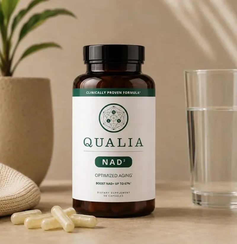 A Qualia NAD bottle with capsules and a glass of water